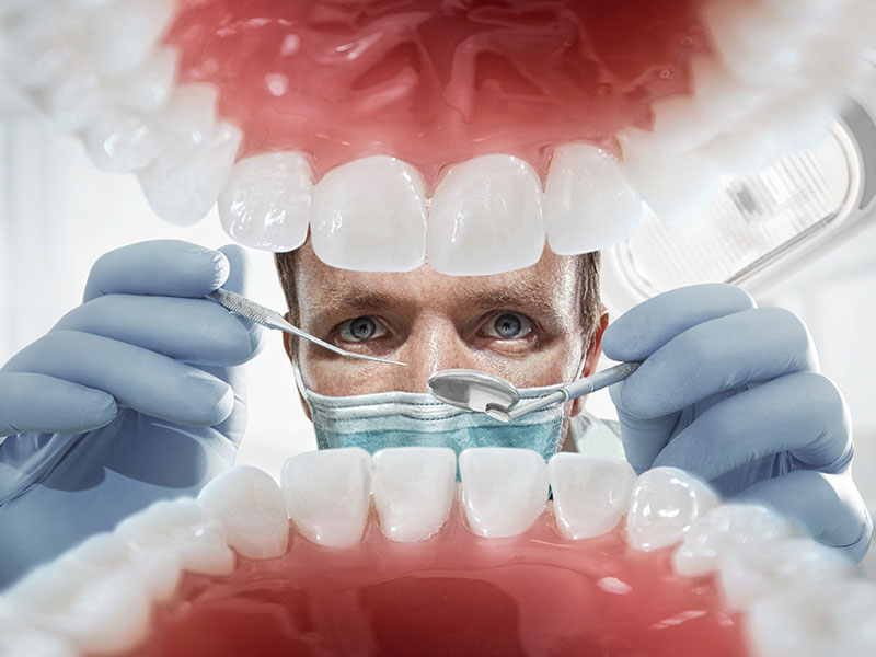 Dentist performing new patient's oral exam in Winnipeg